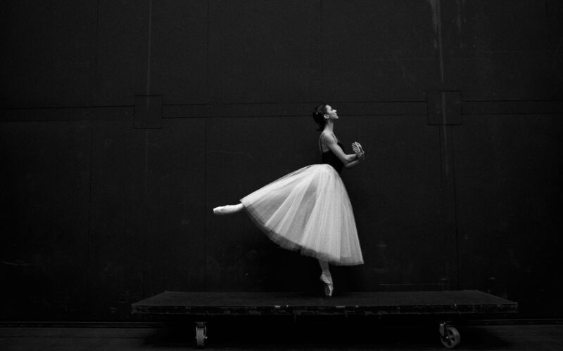 grayscale photography of ballet dancer standing on board